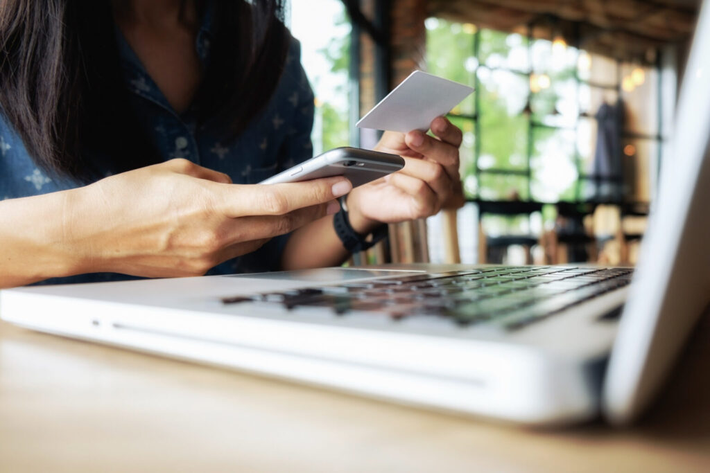 Mujer usando celular, portátil y tarjeta de pago para realizar pagos online con CPS República Dominicana